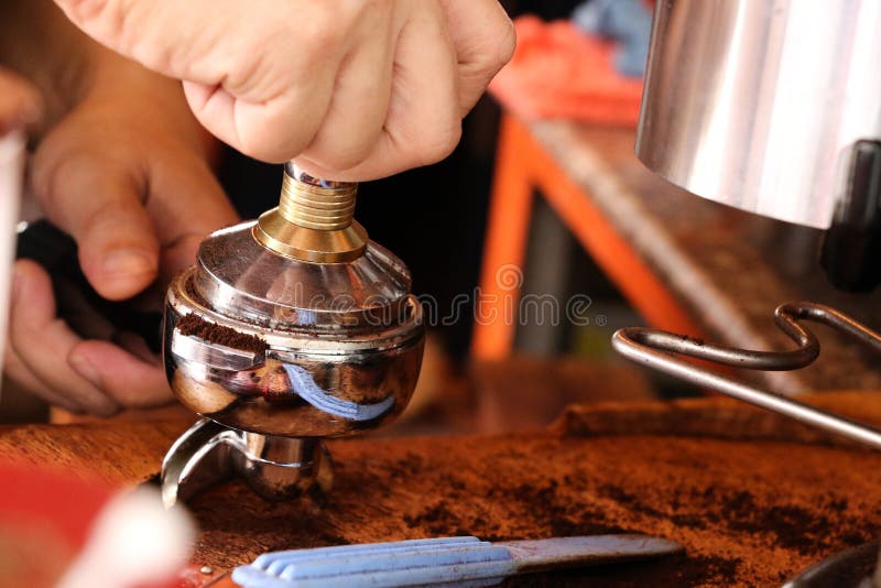 Drücken des gemahlenen Kaffees mit Besetzer lizenzfreie stockbilder Drücken des gemahlenen Kaffees mit Besetzer lizenzfreie stockbilder
