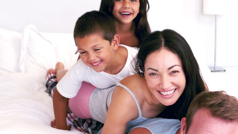 Drăguță familie care se joacă pe patul părinților stock video footage