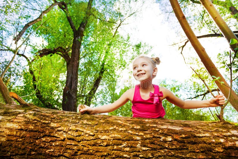 Drăguță fetiță care se uită în spatele copacului căzut stock photography