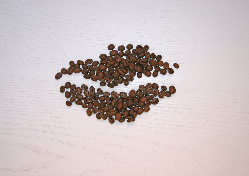 Whole coffee beans on a light background. Whole coffee is laid out in the form of a coffee bean.  Coffee beans are laid out in the form of a single coffee bean with a drawn strip. Whole coffee beans on a light background. Whole coffee is laid out in the form of a coffee bean.  Coffee beans are laid out in the form of a single coffee bean with a drawn strip.