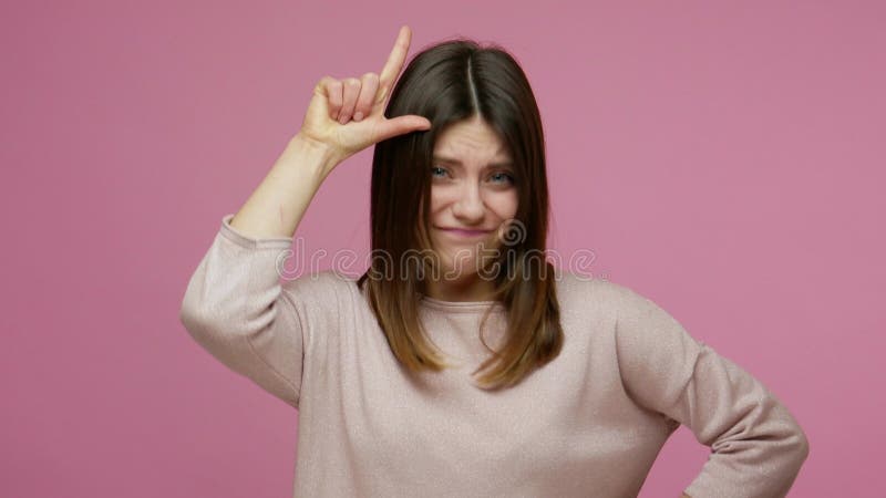 Du förlorar! brunettunge kvinna som gör förlorare, skyler på framsidan och pekar på kamerans teasing
