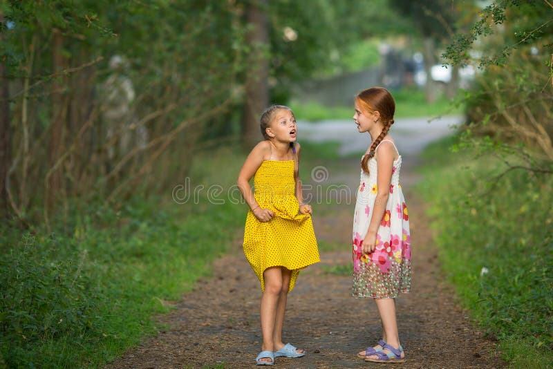 Duas amigas bonitos pequenas que falam animatedly imagem de stock Duas amigas bonitos pequenas que falam animatedly imagem de stock