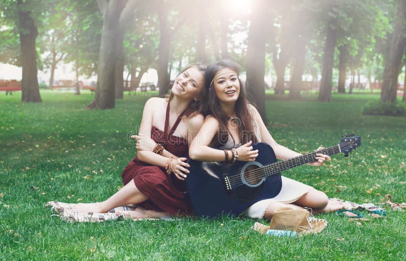Duas amigas à moda chiques do boho feliz com guitarra, piquenique foto de stock Duas amigas à moda chiques do boho feliz com guitarra, piquenique foto de stock