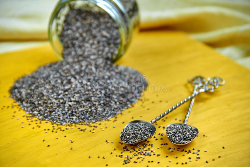 Duas colheres do vintage com as sementes frescas do chia na placa de madeira amarela Superfood saudável cru do chia Frasco de vid fotos de stock royalty free Duas colheres do vintage com as sementes frescas do chia na placa de madeira amarela Superfood saudável cru do chia Frasco de vid fotos de stock royalty free