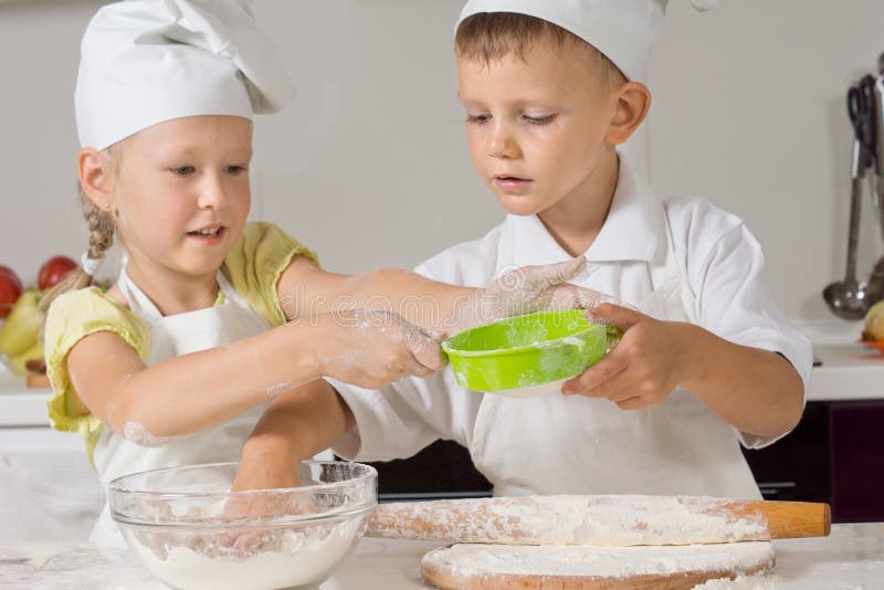 Duas crianças que fazem a pastelaria para bases da pizza