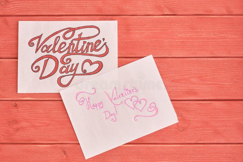 Duas folhas de papel com as inscrição bonitas dedicadas à mentira do dia de Valentim em uma textura da placa de madeira do coral imagens de stock Duas folhas de papel com as inscrição bonitas dedicadas à mentira do dia de Valentim em uma textura da placa de madeira do coral imagens de stock