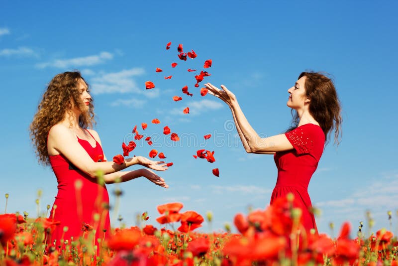 Duas jovens mulheres que jogam no campo das papoilas fotos de stock royalty free Duas jovens mulheres que jogam no campo das papoilas fotos de stock royalty free