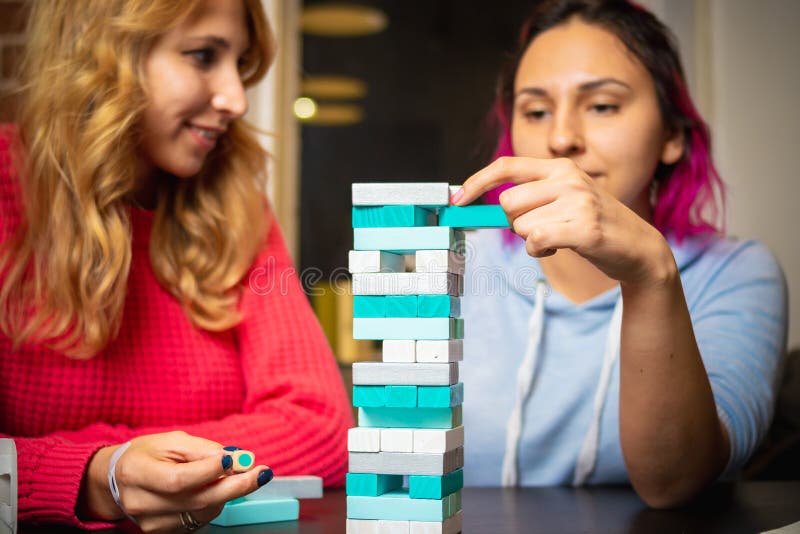 Duas jovens mulheres que jogam o jenga colorido imagens de stock royalty free Duas jovens mulheres que jogam o jenga colorido imagens de stock royalty free
