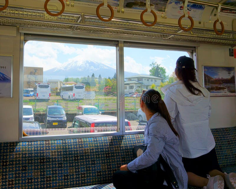 Duas jovens turistas estão olhando pela janela do trem para o Monte Fuji imagens de stock royalty free Duas jovens turistas estão olhando pela janela do trem para o Monte Fuji imagens de stock royalty free