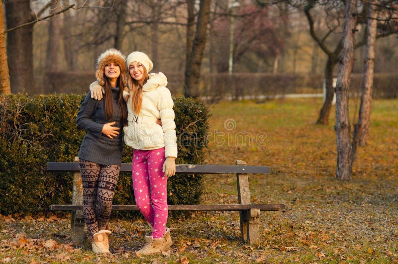 Duas meninas bonitas que têm o divertimento exterior no dia ensolarado do outono foto de stock Duas meninas bonitas que têm o divertimento exterior no dia ensolarado do outono foto de stock
