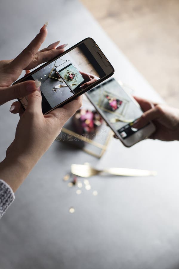 Duas meninas com os telefones nas mãos tomam a imagem do pedaço de bolo bonito foto de stock Duas meninas com os telefones nas mãos tomam a imagem do pedaço de bolo bonito foto de stock
