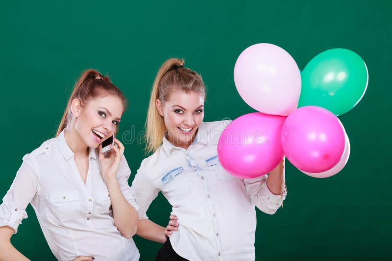 Duas meninas com telefone celular e bal?es fotografia de stock Duas meninas com telefone celular e bal?es fotografia de stock
