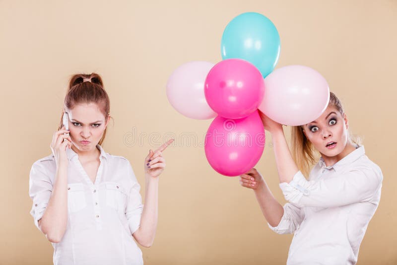 Duas meninas com telefone celular e balões foto de stock Duas meninas com telefone celular e balões foto de stock