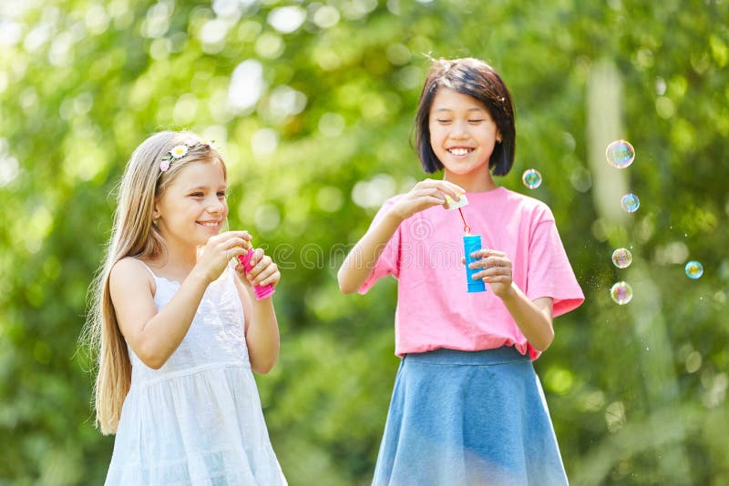Duas meninas estão fazendo bolhas de sabão imagens de stock royalty free Duas meninas estão fazendo bolhas de sabão imagens de stock royalty free