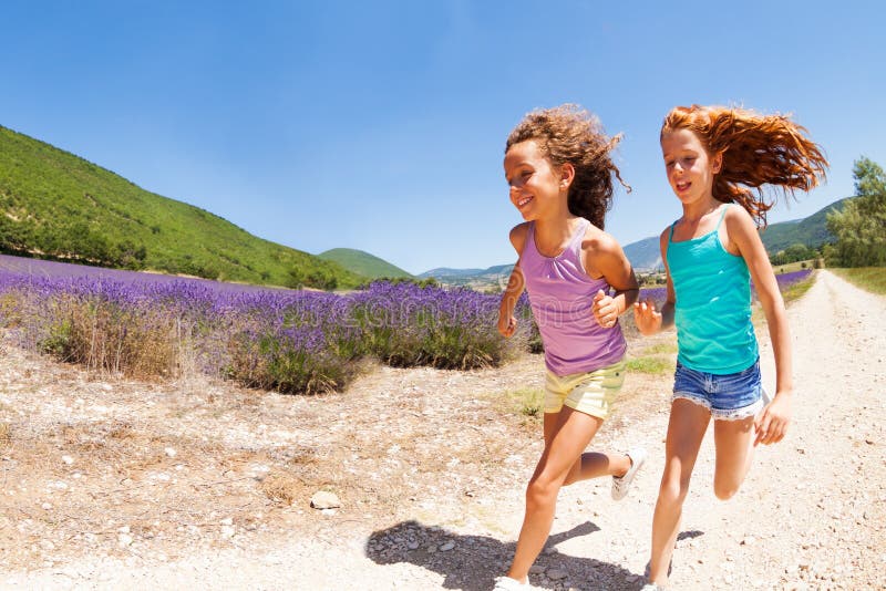 Duas meninas felizes que correm junto no campo da alfazema fotos de stock royalty free Duas meninas felizes que correm junto no campo da alfazema fotos de stock royalty free