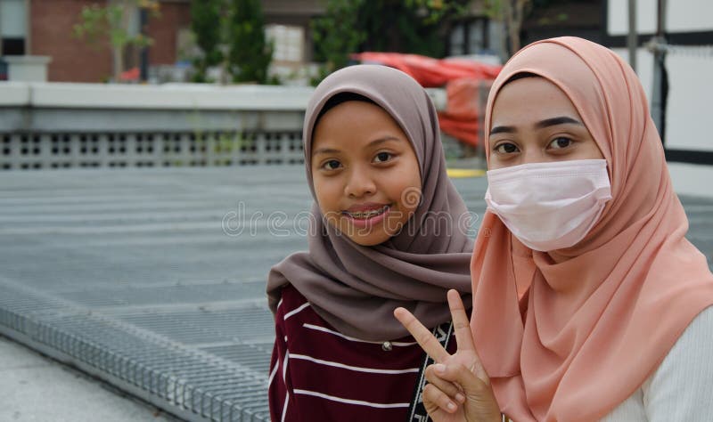 Duas meninas no hijab, um deles que vestem uma máscara imagens de stock royalty free Duas meninas no hijab, um deles que vestem uma máscara imagens de stock royalty free