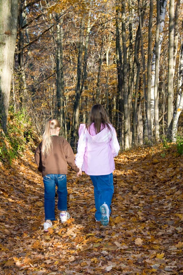 Duas meninas que andam em conjunto na floresta. imagens de stock Duas meninas que andam em conjunto na floresta. imagens de stock