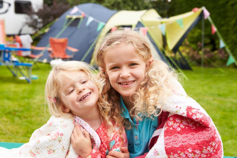 Duas meninas que relaxam na cobertura durante o feriado de acampamento da família imagens de stock royalty free Duas meninas que relaxam na cobertura durante o feriado de acampamento da família imagens de stock royalty free
