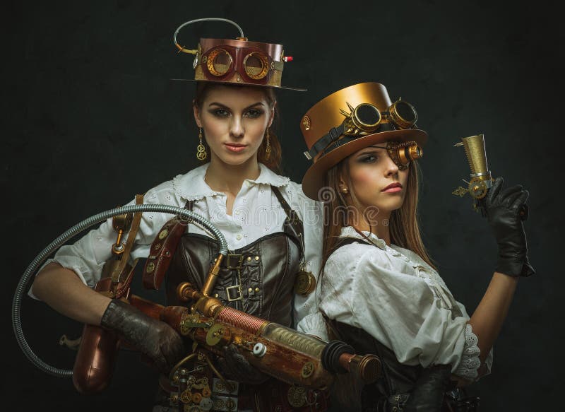 Duas meninas vestidas ao estilo do steampunk com braços imagem de stock royalty free Duas meninas vestidas ao estilo do steampunk com braços imagem de stock royalty free