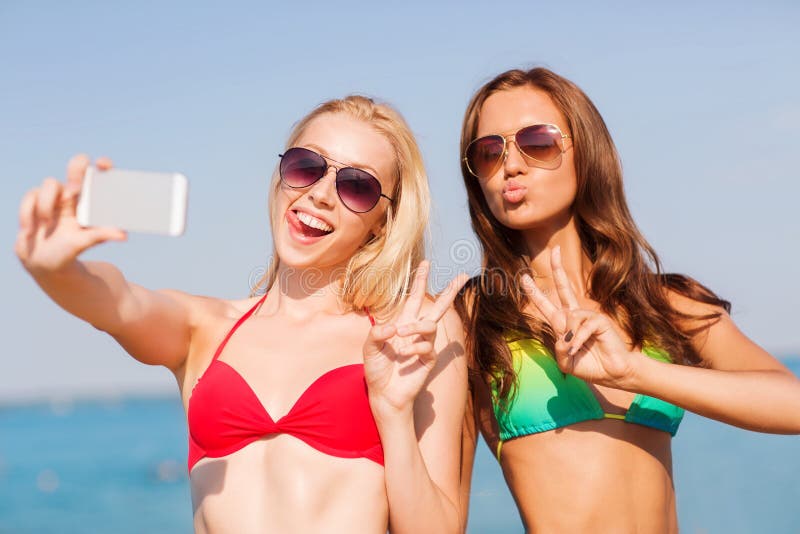 Duas mulheres de sorriso que fazem o selfie na praia imagens de stock Duas mulheres de sorriso que fazem o selfie na praia imagens de stock