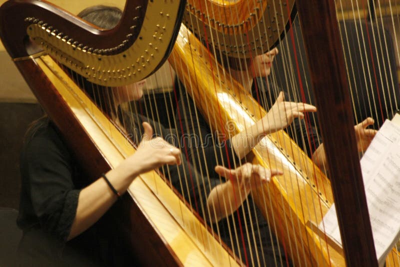 Duas mulheres jogam a harpa durante um concerto sinfônico