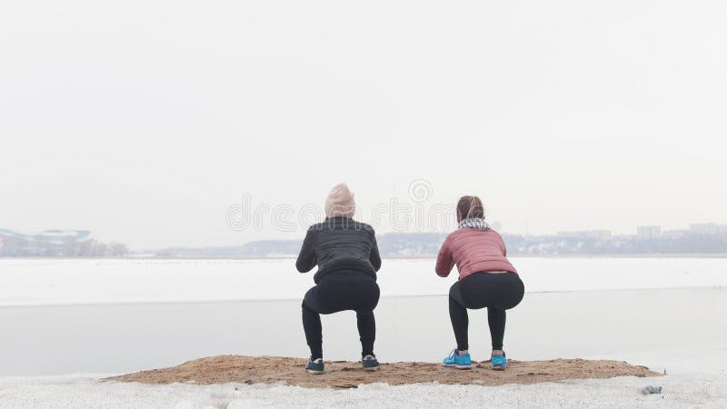 Duas mulheres magros que estão na praia nevado e que fazem ocupas fotografia de stock royalty free Duas mulheres magros que estão na praia nevado e que fazem ocupas fotografia de stock royalty free