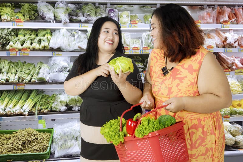 Duas mulheres obesos que compram vegetais orgânicos fotografia de stock Duas mulheres obesos que compram vegetais orgânicos fotografia de stock