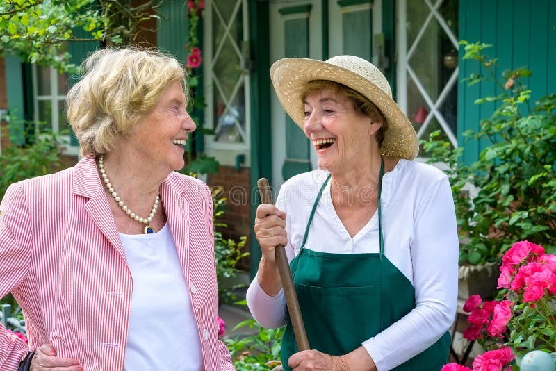 Duas mulheres superiores que riem junto no jardim fotografia de stock Duas mulheres superiores que riem junto no jardim fotografia de stock