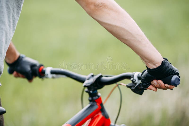 Duas mãos masculinas nas luvas que guardam o guiador da bicicleta fotografia de stock royalty free Duas mãos masculinas nas luvas que guardam o guiador da bicicleta fotografia de stock royalty free