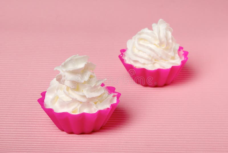 Two portions of whipped cream over pink background. Shallow DOF. Two portions of whipped cream over pink background. Shallow DOF