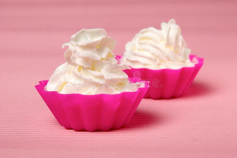 Two portions of whipped cream over pink background. Shallow DOF. Two portions of whipped cream over pink background. Shallow DOF