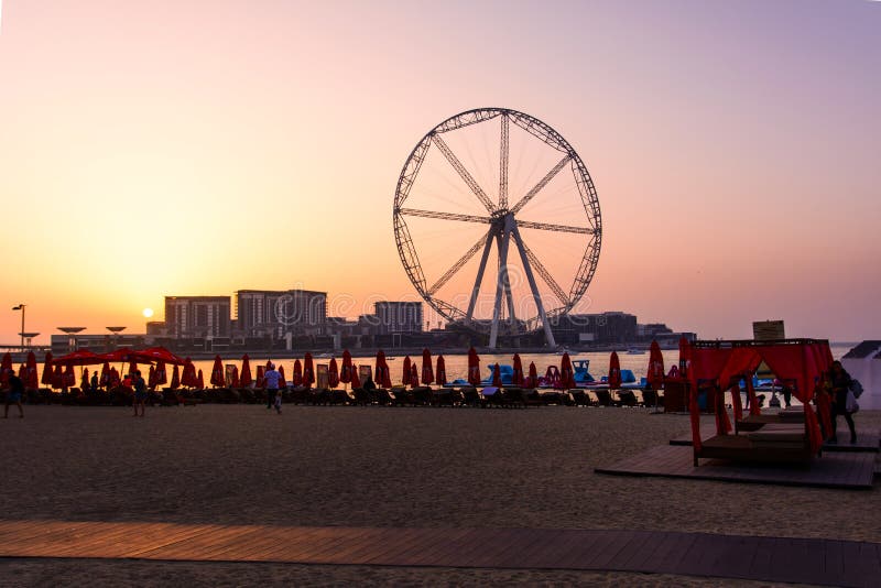 Dubai, United Arab Emirates - March 8, 2018: Sunbeds and romantic sunset at JBR, Jumeira Beach Resort beach with ferris wheel in royalty free stock photos Dubai, United Arab Emirates - March 8, 2018: Sunbeds and romantic sunset at JBR, Jumeira Beach Resort beach with ferris wheel in royalty free stock photos