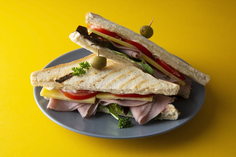 Dubbeldekker met geïsoleerde ham Geroosterde dubbele panini met ham, kaas verse groenten Gele achtergrond royalty-vrije stock fotografie Dubbeldekker met geïsoleerde ham Geroosterde dubbele panini met ham, kaas verse groenten Gele achtergrond royalty-vrije stock fotografie