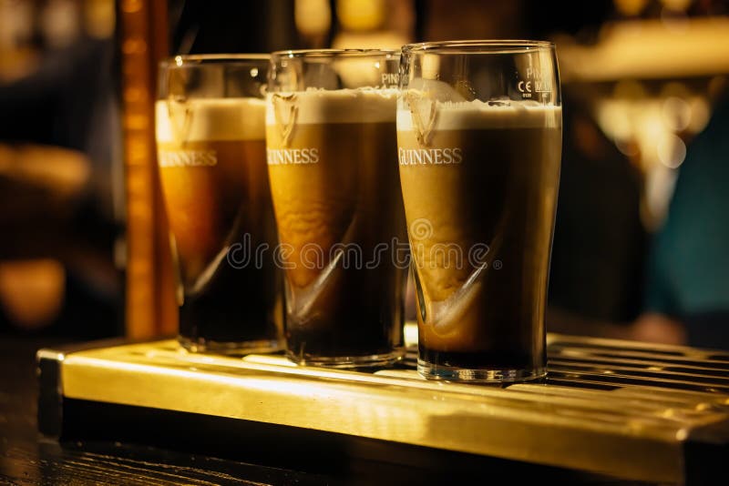 Selective focus on three pints of Guinness in glasses on bar or tap
