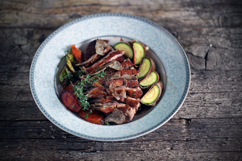 Duck breast sliced with black truffles and vegetables, thyme