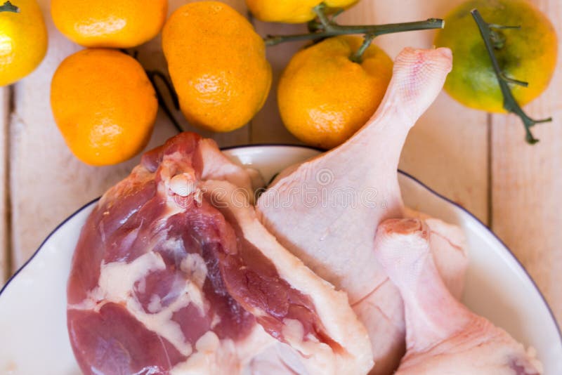 Duck Meat Fresh, Raw Duck Legs with Fruit on a Wooden Surface. Stock