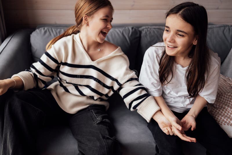 Due adolescenti sedute su un divano che ridono fotografie stock
