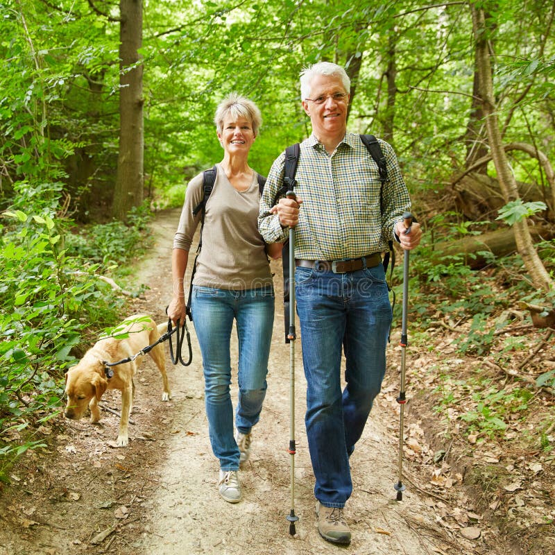 Due anziani che camminano con il cane in foresta
