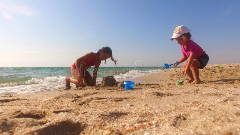 Due bambini che costruiscono il castello della sabbia sulla spiaggia