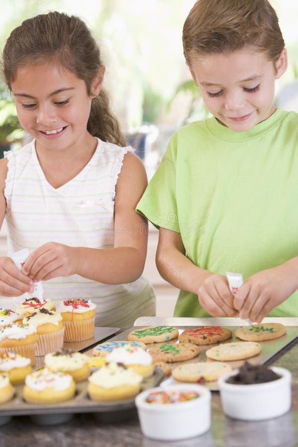 Due bambini in cucina che decorano i biscotti immagine stock libera da diritti Due bambini in cucina che decorano i biscotti immagine stock libera da diritti