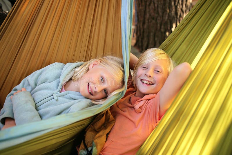 Due bambini felici che sorridono come rilassati su un'amaca in un giorno d'estate fotografia stock libera da diritti