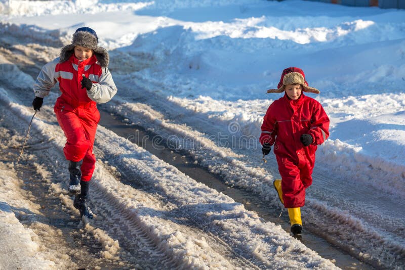 Due bambini nei rainboots che corrono sul ghiaccio sguazzano fotografia stock libera da diritti Due bambini nei rainboots che corrono sul ghiaccio sguazzano fotografia stock libera da diritti