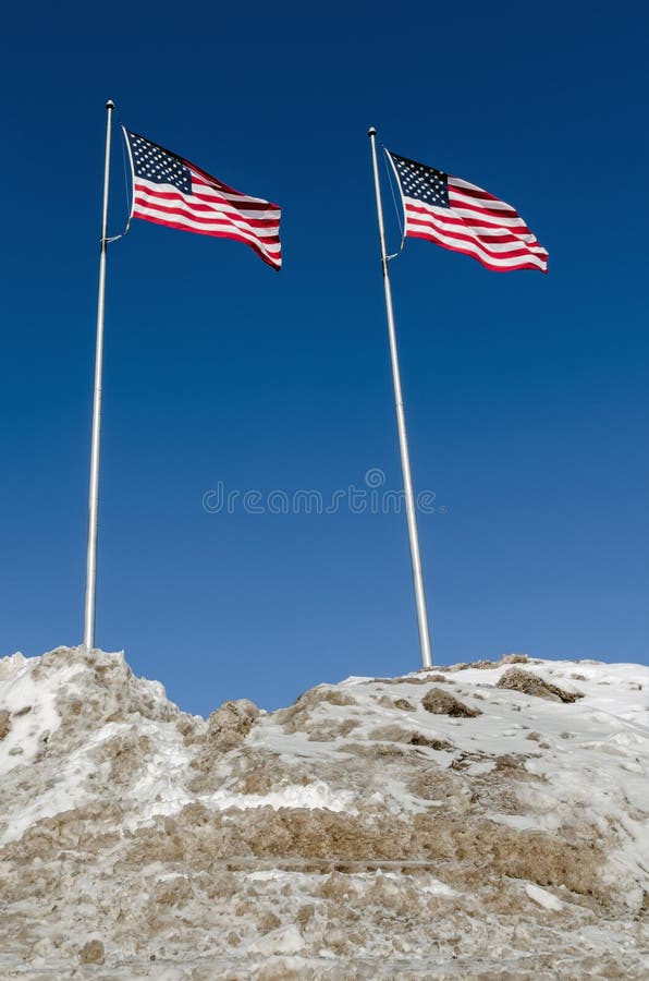 Due bandiere americane dietro il mucchio inquinante della neve fotografia stock libera da diritti Due bandiere americane dietro il mucchio inquinante della neve fotografia stock libera da diritti