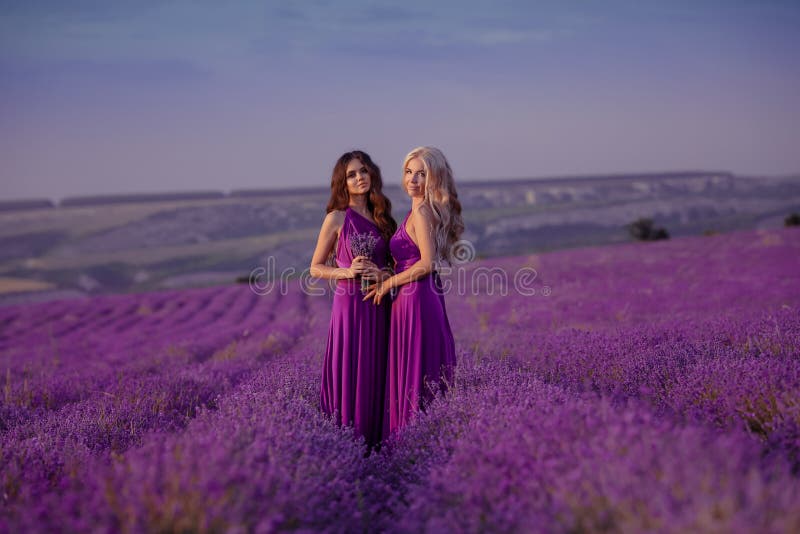 Due belle donne spensierate che godono del tramonto nel giacimento della lavanda armonia Biondo e castana attraenti con stile di immagini stock libere da diritti Due belle donne spensierate che godono del tramonto nel giacimento della lavanda armonia Biondo e castana attraenti con stile di immagini stock libere da diritti