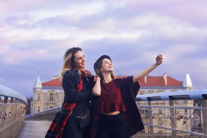 Due belle giovani amiche dello studente divertendosi facendo i fronti divertenti e prendendo gli autoritratti con lo Smart Phone fotografie stock libere da diritti Due belle giovani amiche dello studente divertendosi facendo i fronti divertenti e prendendo gli autoritratti con lo Smart Phone fotografie stock libere da diritti