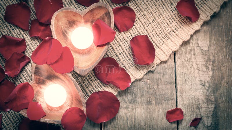 Due candele chiarite in candelieri in forma di cuore con sono aumentato immagine stock Due candele chiarite in candelieri in forma di cuore con sono aumentato immagine stock