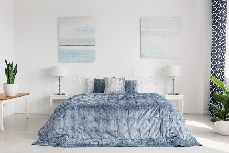 Due che dipingono sulla parete della camera da letto luminosa elegante interni con lettiera accogliente e mobilia bianca immagine stock