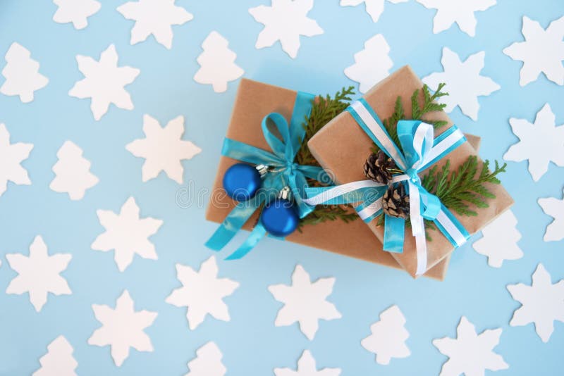 Due contenitori di regalo avvolti della carta del mestiere, nastro blu e bianco e rami decorati dell'abete, palle blu di Natale e immagini stock Due contenitori di regalo avvolti della carta del mestiere, nastro blu e bianco e rami decorati dell'abete, palle blu di Natale e immagini stock