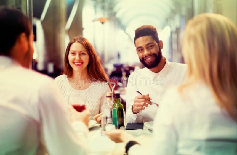 Due coppie felici che si siedono al ristorante all'aperto fotografia stock libera da diritti Due coppie felici che si siedono al ristorante all'aperto fotografia stock libera da diritti