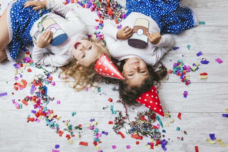 Due coriandoli variopinti di modo del bambino delle bambine sul pavimento fotografia stock libera da diritti Due coriandoli variopinti di modo del bambino delle bambine sul pavimento fotografia stock libera da diritti